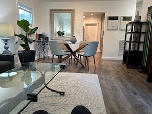 Relax in this stylish living room with a glass coffee table, two armchairs, and a dining area with four chairs.