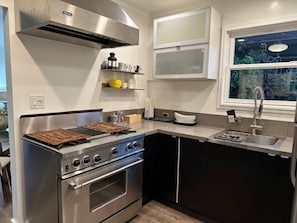 Enjoy cooking in this well-equipped kitchen with a stainless steel range hood, oven, and double sink.