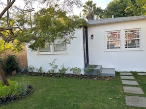 Simple, single-story home with a front porch and well-manicured yard.