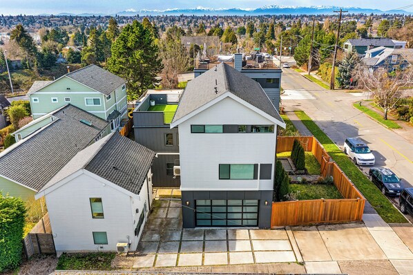 Un quartier résidentiel avec des maisons modernes, une allée bien dégagée et une vue sur une ville lointaine.