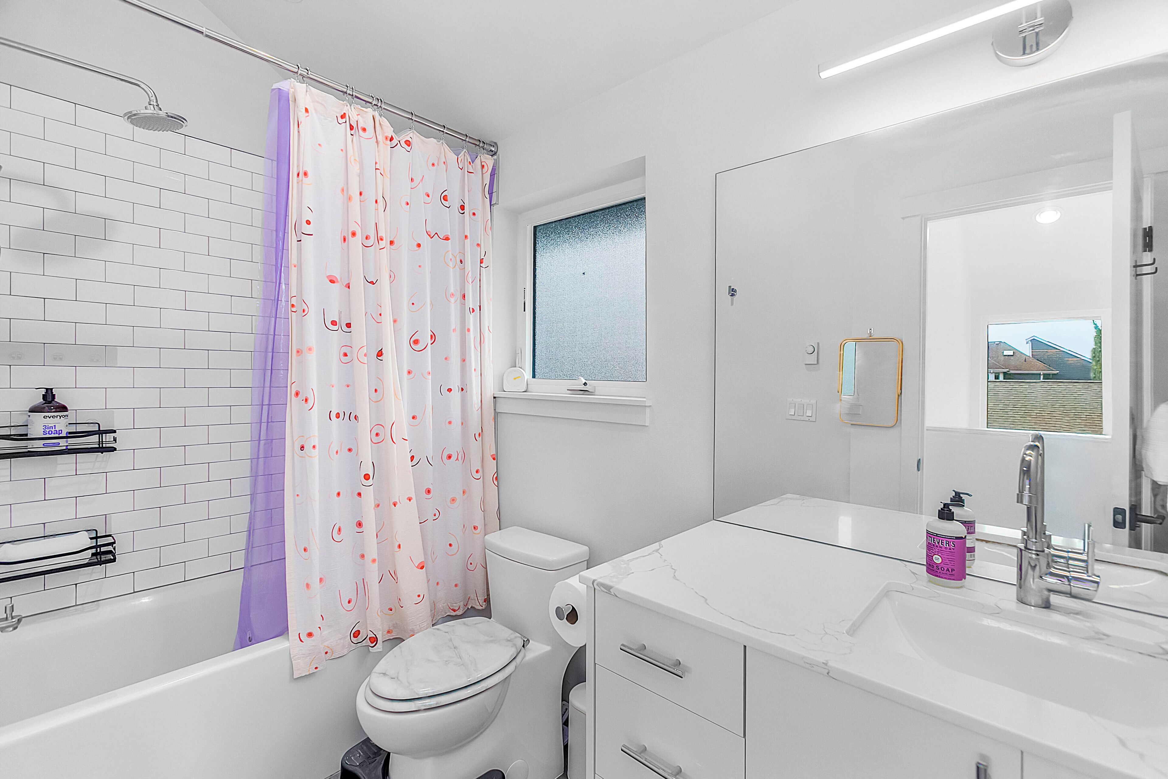 Een moderne badkamer met een bad, toilet en wastafel.