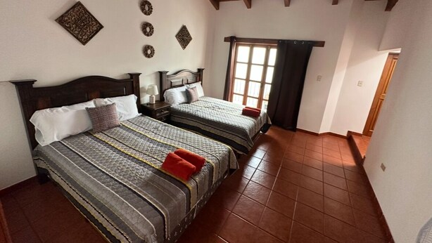 Un dormitorio con dos camas, techo de madera y una ventana con cortinas.