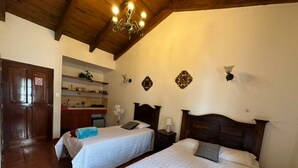 Habitación de hotel con dos camas, techo de madera, zona de cocina y una puerta con un cartel de 'No Entry'.