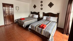 Una habitación con dos camas, cada una con cabecero de madera, mesita de noche y lámpara de pared.