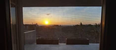 Un balcón con vista al atardecer y un paisaje lejano.