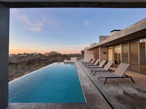 A swimming pool with lounge chairs and a view of the surrounding landscape. - Arroyo Escondido -Luxe Oceanview Contemporary Home (Todos Santos)