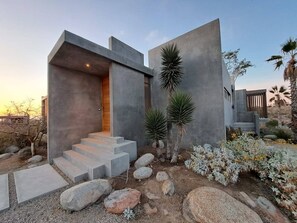A modern house with a concrete exterior, a wooden door, and a set of concrete stairs leading to the entrance. - Arroyo Escondido -Luxe Oceanview Contemporary Home (Todos Santos)