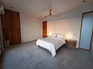 A bedroom with a bed, bedside tables, a wardrobe, and a ceiling fan.