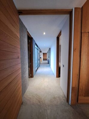 A corridor with wooden walls, a carpeted floor, and a door at the end.