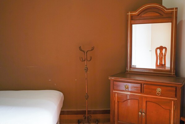 A room with a bed, a wooden dresser with a mirror, and a coat stand. - Hotel El Conquistador (Veracruz)