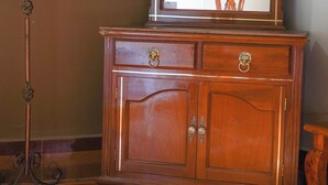 A wooden dresser with a mirror, drawers, and a decorative metal stand. - OYO Hotel El Conquistador (Veracruz)