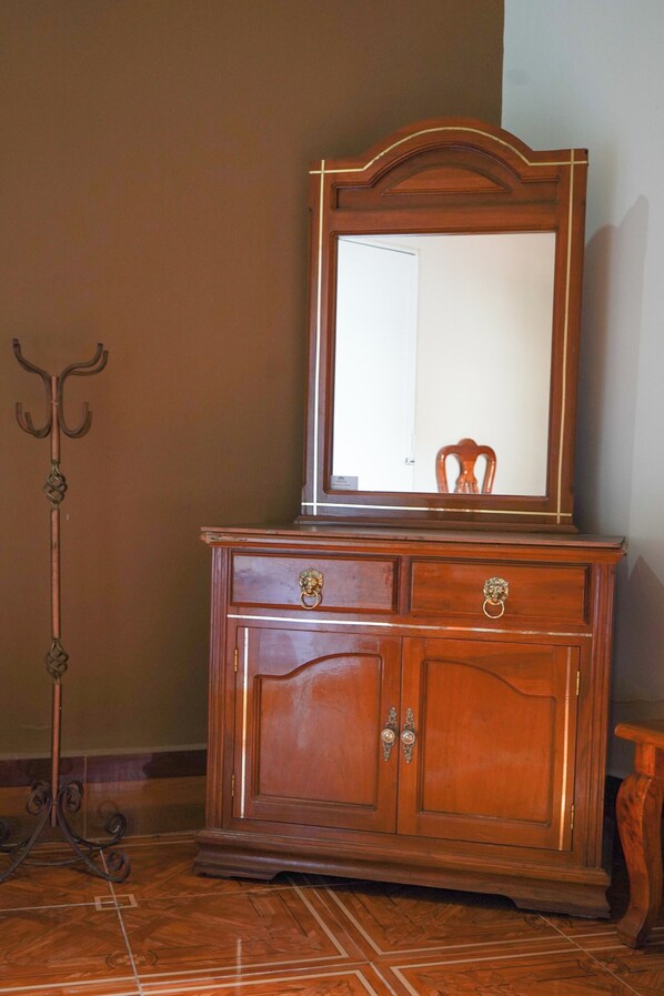 A wooden dresser with a mirror, drawers, and a decorative metal stand. - Hotel El Conquistador (Veracruz)