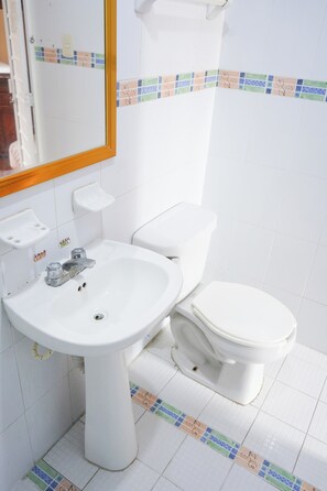 A bathroom with a white sink, toilet, and mirror. - Hotel El Conquistador (Veracruz)