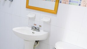 A bathroom with a white sink, toilet, and a mirror with a gold frame. - Hotel El Conquistador (Veracruz)