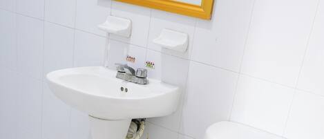A bathroom with a white sink, toilet, and a mirror with a gold frame.