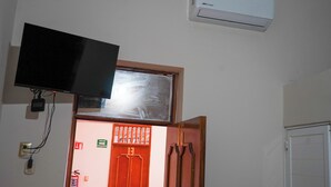 A room with a mounted television, an air conditioning unit, and a red door with a window. - OYO Hotel El Conquistador (Veracruz)