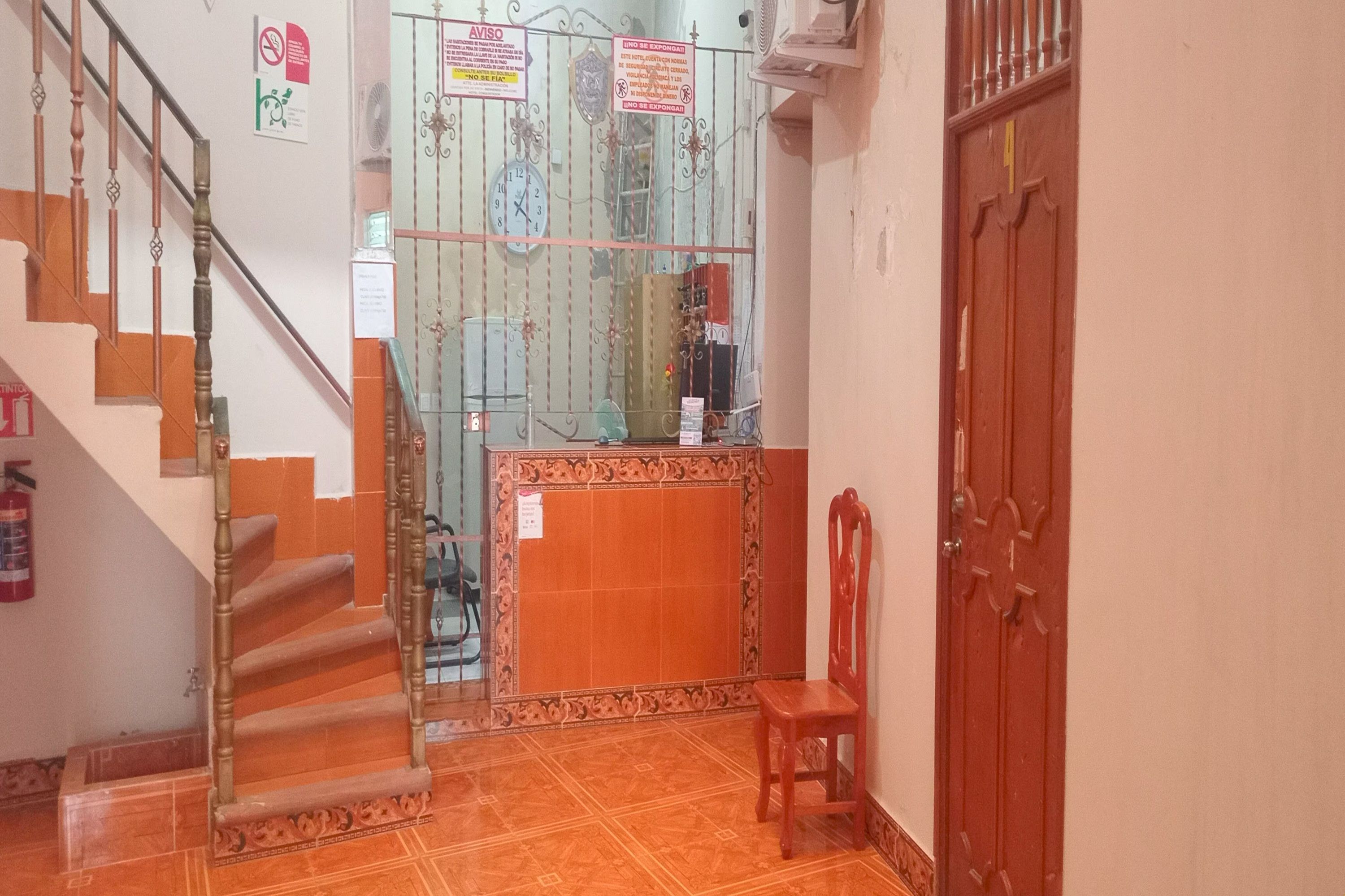 Una escalera conduce a una plataforma con una puerta de vidrio, un banco de madera y un extintor en la pared.