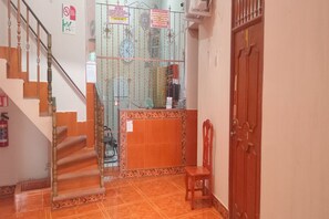 A staircase leading to a landing with a glass door, a wooden bench, and a fire extinguisher on the wall. - Hotel El Conquistador (Veracruz)