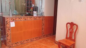 A reception area with a wooden counter, a chair, and a glass partition. - Hotel El Conquistador (Veracruz)