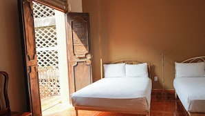 A bedroom with a wooden bed, a wooden chair, and a large wooden door with a lattice design. - OYO Hotel El Conquistador (Veracruz)