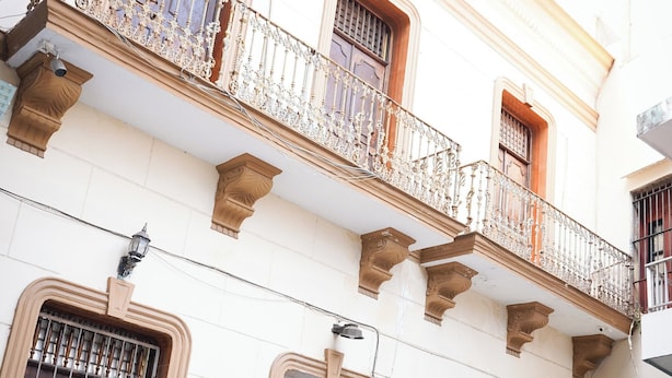 A building with a balcony, multiple doors, and a small plant. - OYO Hotel El Conquistador (Veracruz)