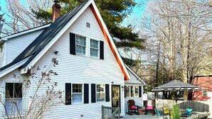 Et hvidt hus med sorte skodder, en overdækket veranda og nummer 96 på døren.