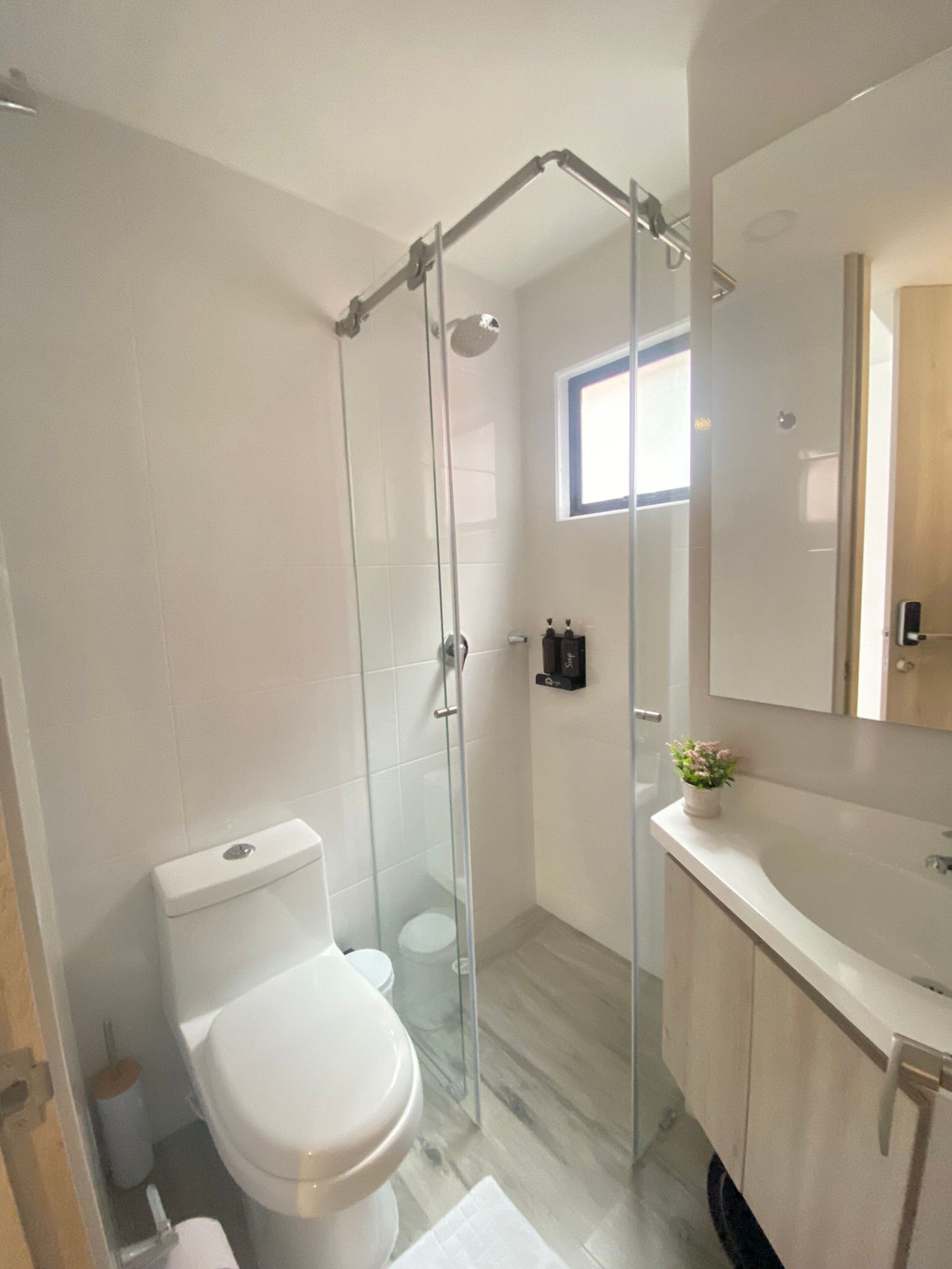 Een moderne badkamer met een douchecabine, een toilet, een wastafel en een spiegel.