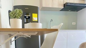 Una cocina moderna con una silla blanca, una mesa de madera y un refrigerador.