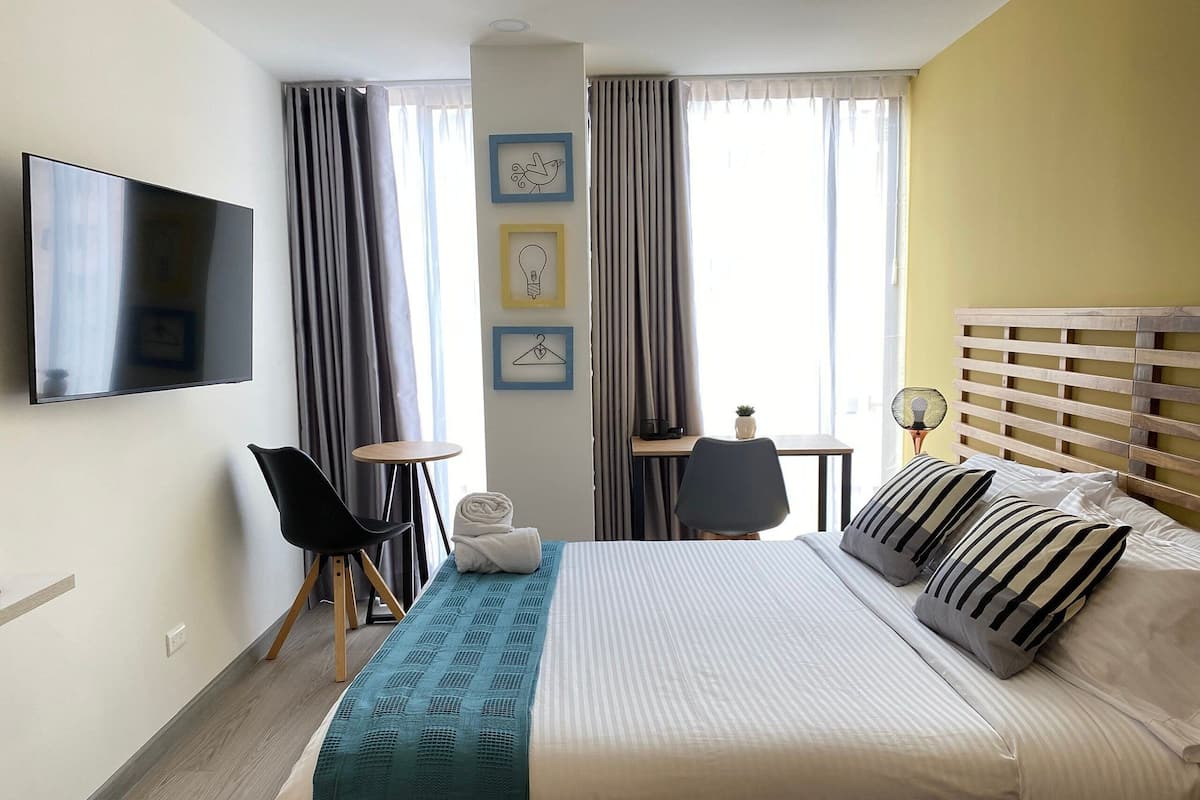 A hotel room with a bed, a TV, a desk, and a chair.