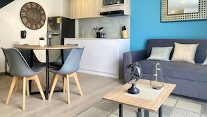 Una cocina moderna con microondas, un reloj y un comedor con sillas y una mesa.