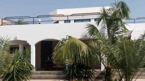 A modern building with a white facade, arched entrance, and a balcony.