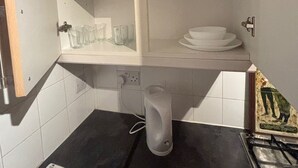 A kitchen with white cabinets, a black countertop, a stove, and a small trash bin. - Stylish 1-bed Apartment- Sleeps 3 w/ Central Links (Pinner)