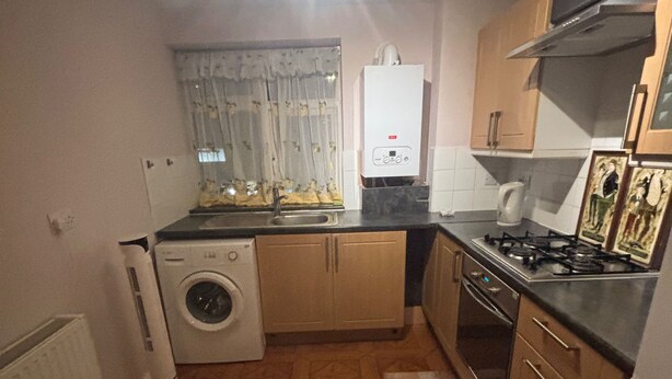 A compact kitchen with a washing machine, a stove, and a sink. - Stylish 1-bed Apartment- Sleeps 3 w/ Central Links (Pinner)