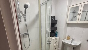 A modern bathroom with a glass-enclosed shower, a white sink, and a mirror cabinet. - Stylish 1-bed Apartment- Sleeps 3 w/ Central Links (Pinner)