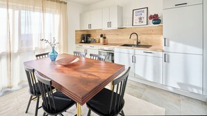 Een moderne keuken met witte kasten, een houten aanrecht en een eethoek met een houten tafel en stoelen.