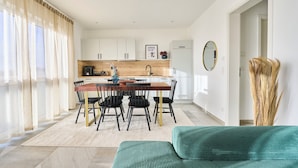 Een moderne keuken met witte kastjes, een houten aanrecht en een zithoek met een tafel en stoelen.