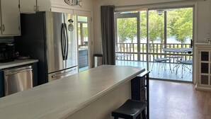 Una cocina con una isla grande, electrodomésticos de acero inoxidable y vistas a una terraza a través de amplios ventanales.