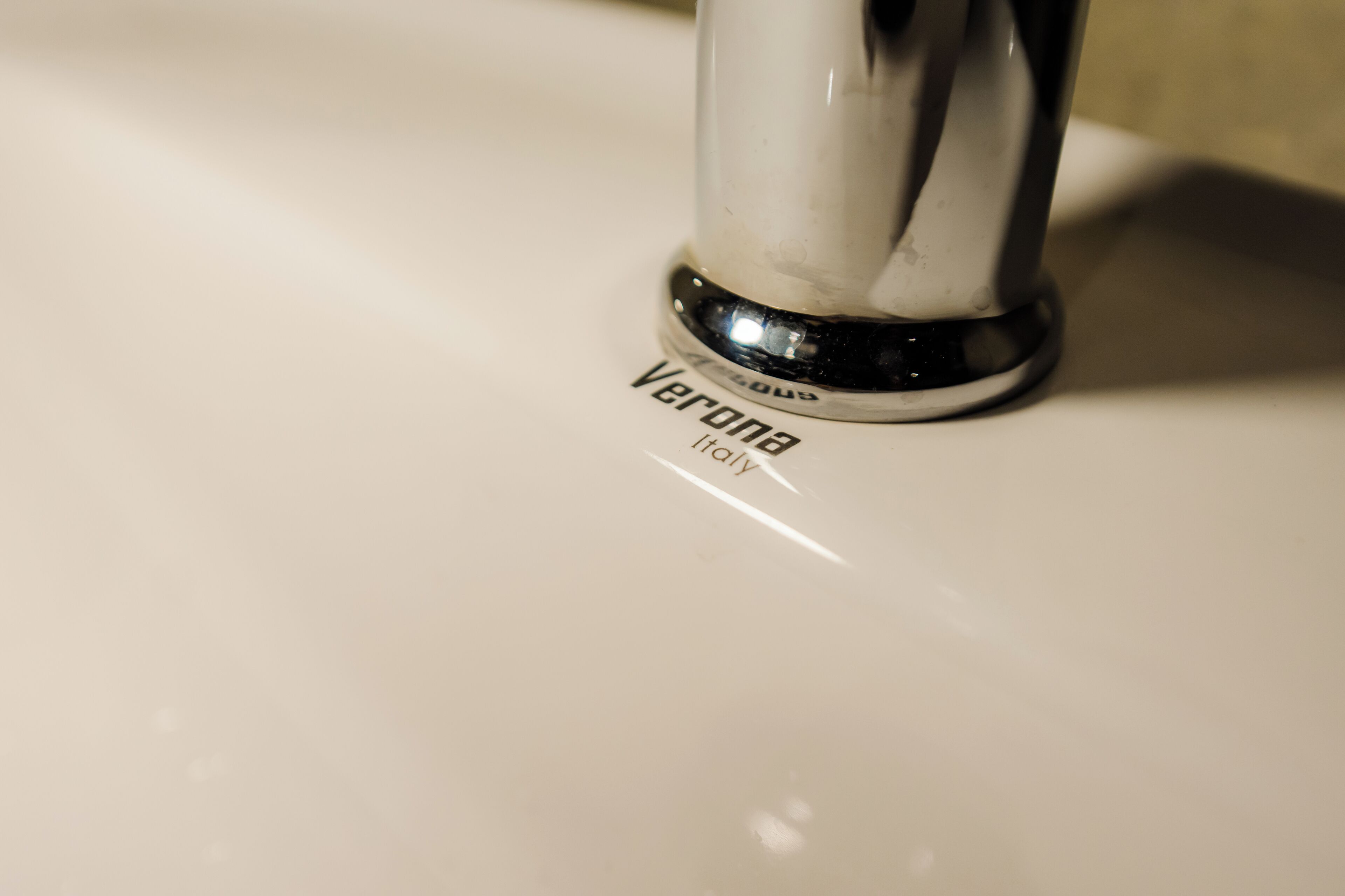 A close-up of a sink faucet with the brand name "Verona" visible.