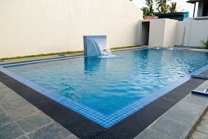 A rectangular swimming pool with a blue tiled border and a waterfall feature. - White on White (Hikkaduwa)
