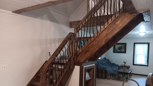 A wooden staircase with metal railings leading to an upper floor.