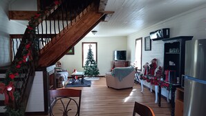 A cozy living room with a wooden staircase, a Christmas tree, a television, and a refrigerator.