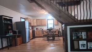 A kitchen with wooden cabinets, a refrigerator, and a dining area with chairs and a table.