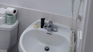 Un bagno con lavandino bianco, specchio, asciugacapelli e articoli da toilette.