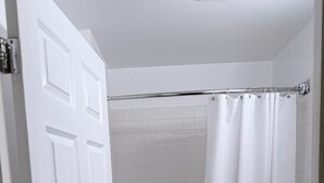 Un bagno con una porta bianca, una vasca, una tenda da doccia e un water.