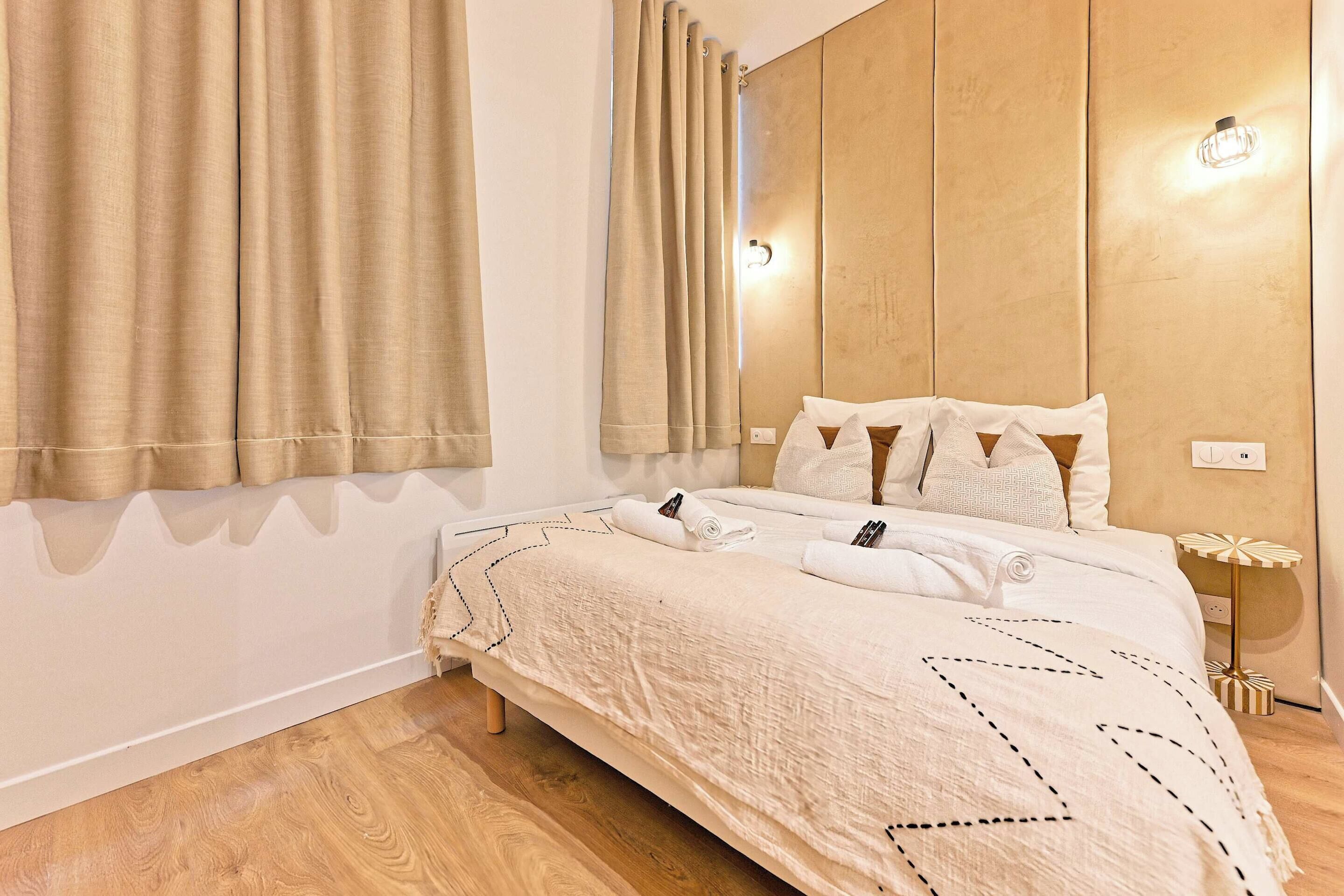 A neatly made bed with a white duvet, a wooden headboard, and a bedside table with a lamp.