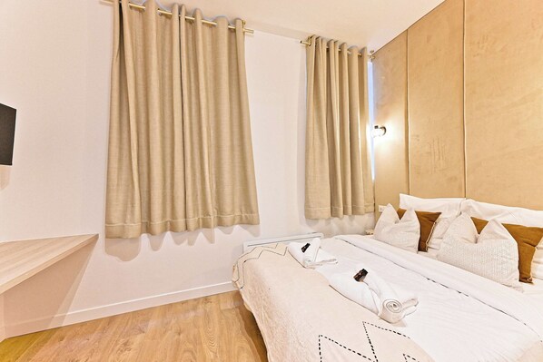A hotel room with a bed, curtains, a wooden headboard, and a flat-screen TV mounted on the wall. - Superb Air-conditioned Flat Galeries Lafayette (Paris)