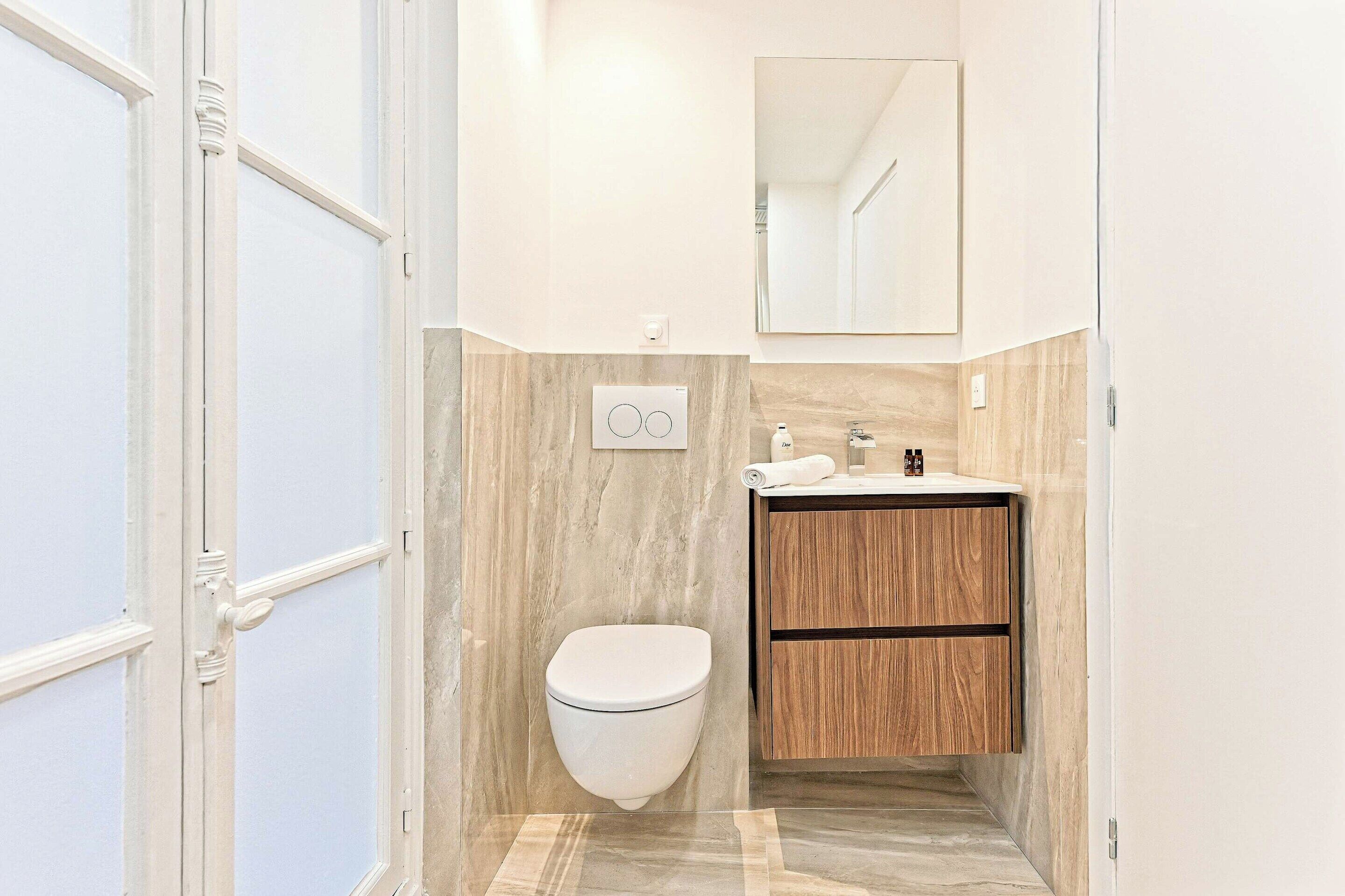 A bathroom with a toilet, sink, and mirror.