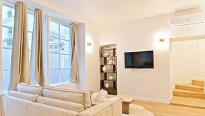 Ein Wohnzimmer mit einem beigefarbenen Sofa, einem Flachbildfernseher und einer Treppe.