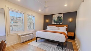 Ein modernes Schlafzimmer mit einem großen Bett, einem Heizkörper, einem Fenster mit Ausblick und einem Deckenventilator.