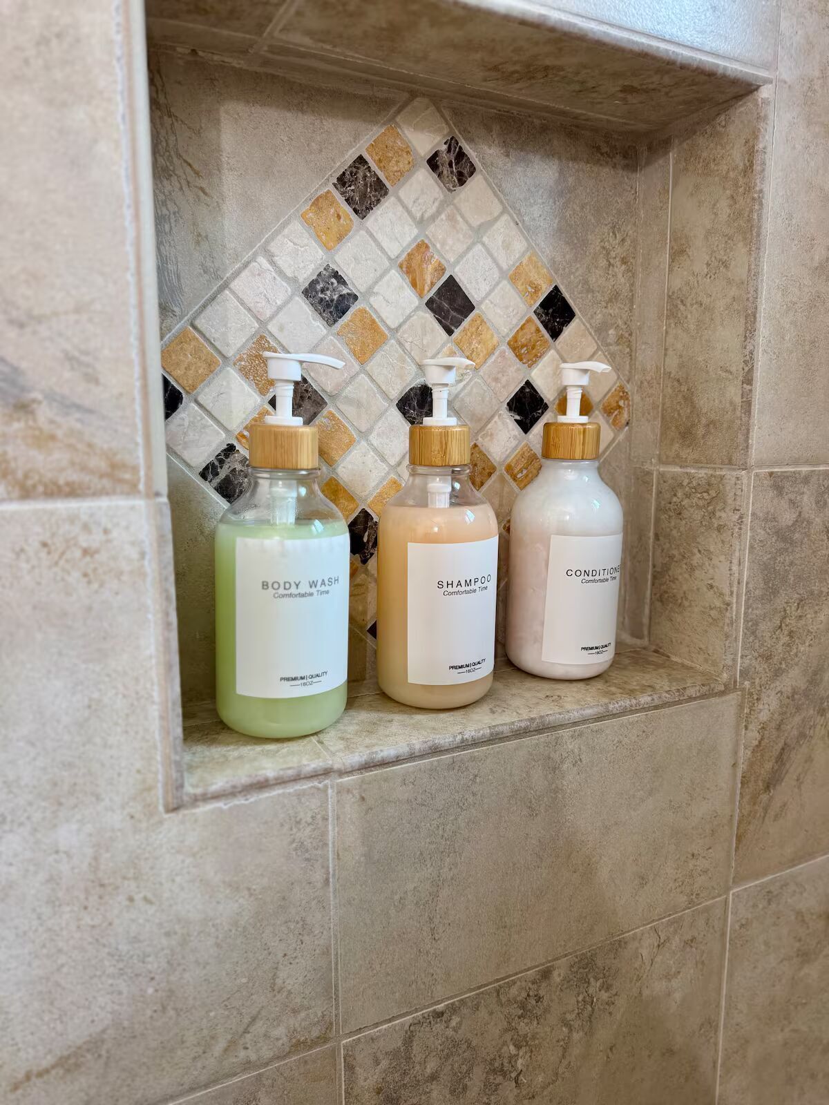Ein Badezimmerschrank mit drei Flaschen Duschgel, Shampoo und Conditioner.